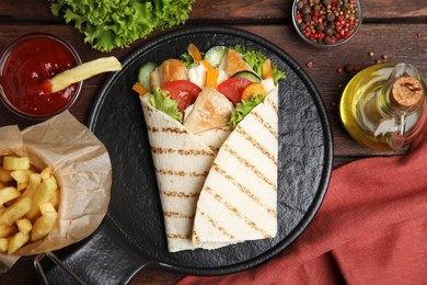 Delicious shawarma with chicken meat and vegetables  served on wooden table, flat lay