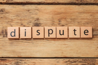 Photo of Squares with word Dispute on wooden table, top view