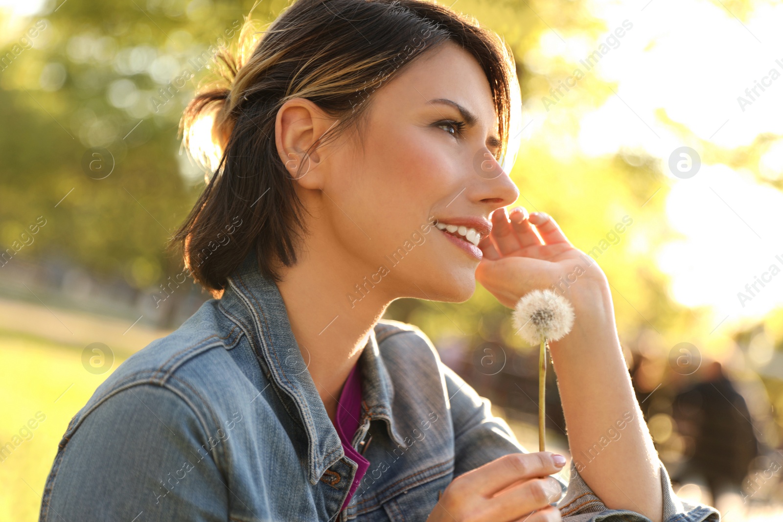 Photo of Young woman with dandelion in park on sunny day. Allergy free concept