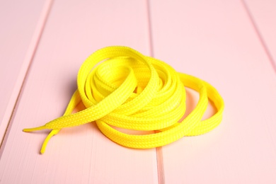 Photo of Yellow shoelace on pink wooden background. Stylish accessory