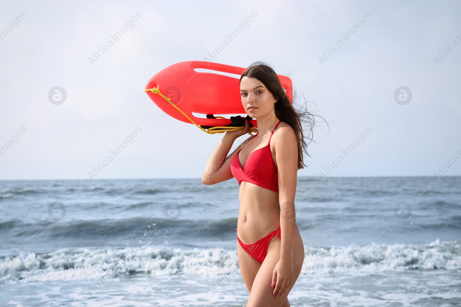 Photo of Beautiful young lifeguard with life buoy near sea