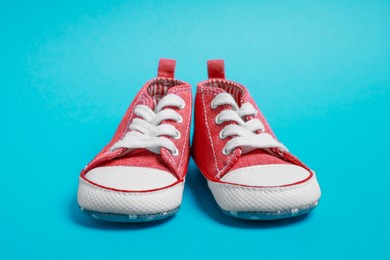 Photo of Pair of cute baby shoes on light blue background