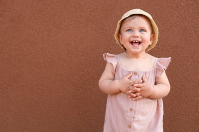 Photo of Cute little girl wearing stylish clothes near brown wall. Space for text