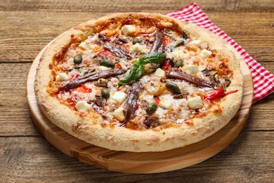 Photo of Tasty pizza with anchovies, basil and olives on wooden table