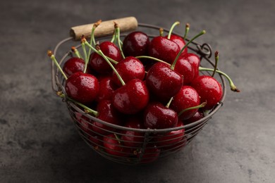 Photo of Metal basket with ripe sweet cherries on dark grey table, closeup