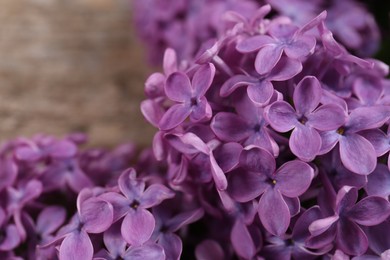 Photo of Beautiful lilac flowers on wooden table, closeup