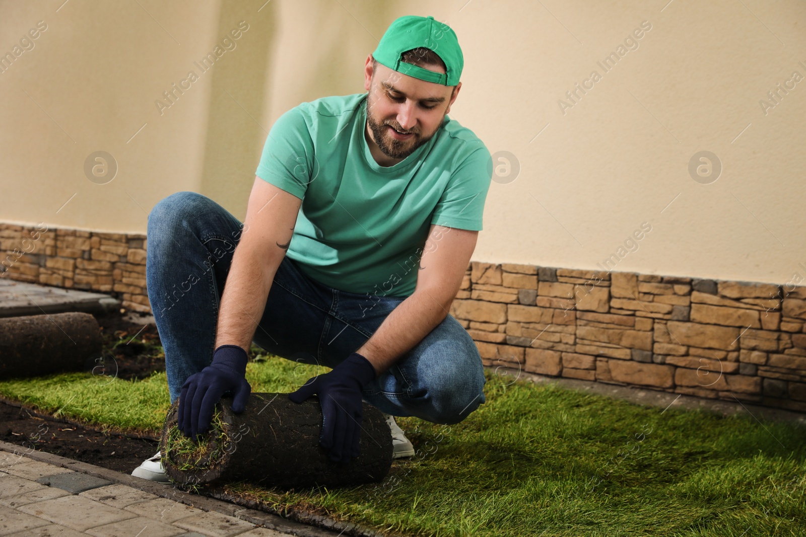 Photo of Worker laying grass sod on ground at backyard