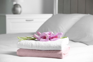 Photo of Terry towels with beautiful flower on bed indoors, space for text
