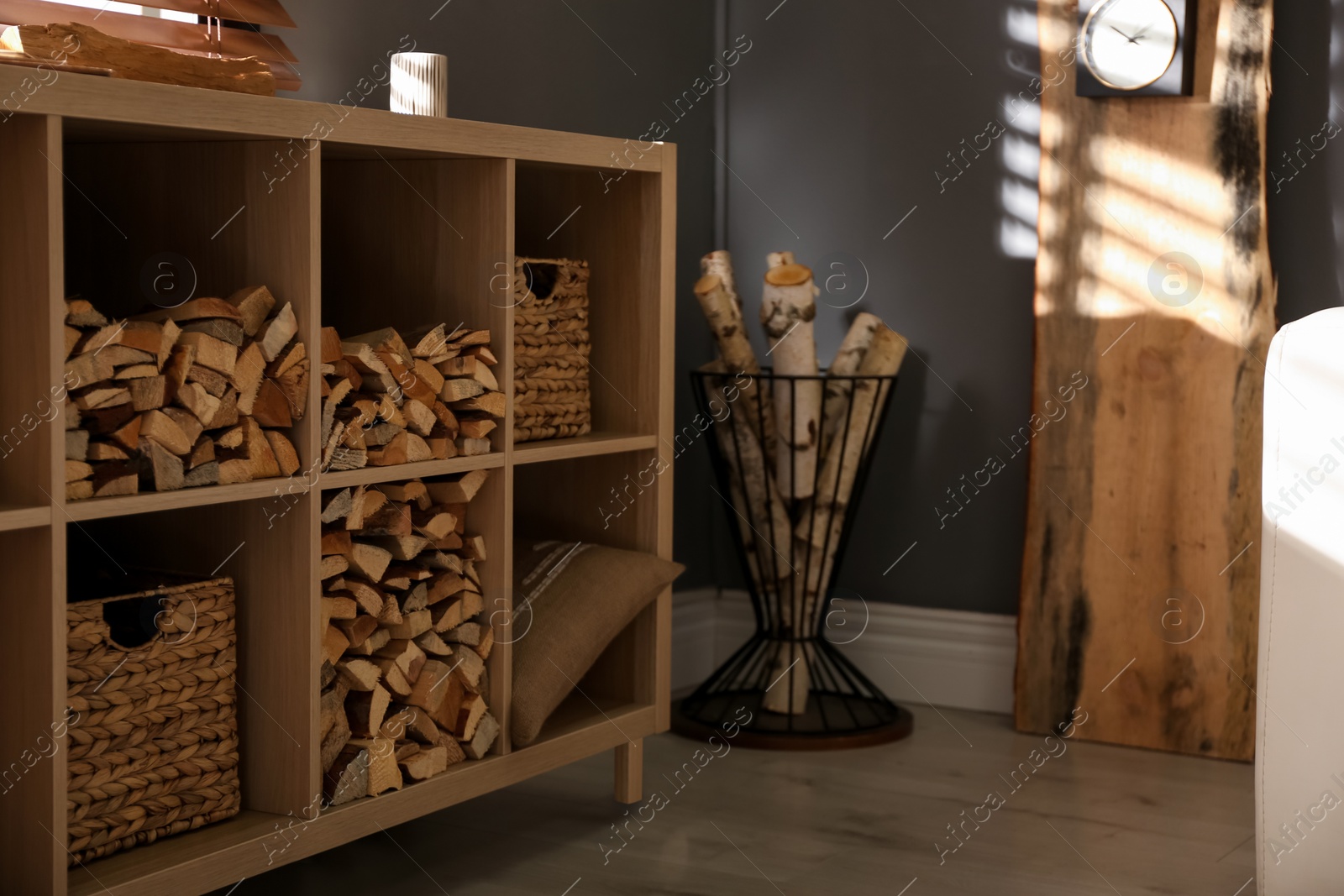 Photo of Shelving unit with stacked firewood in stylish room interior