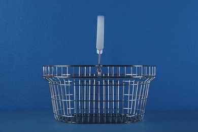 Empty metal shopping basket on blue background