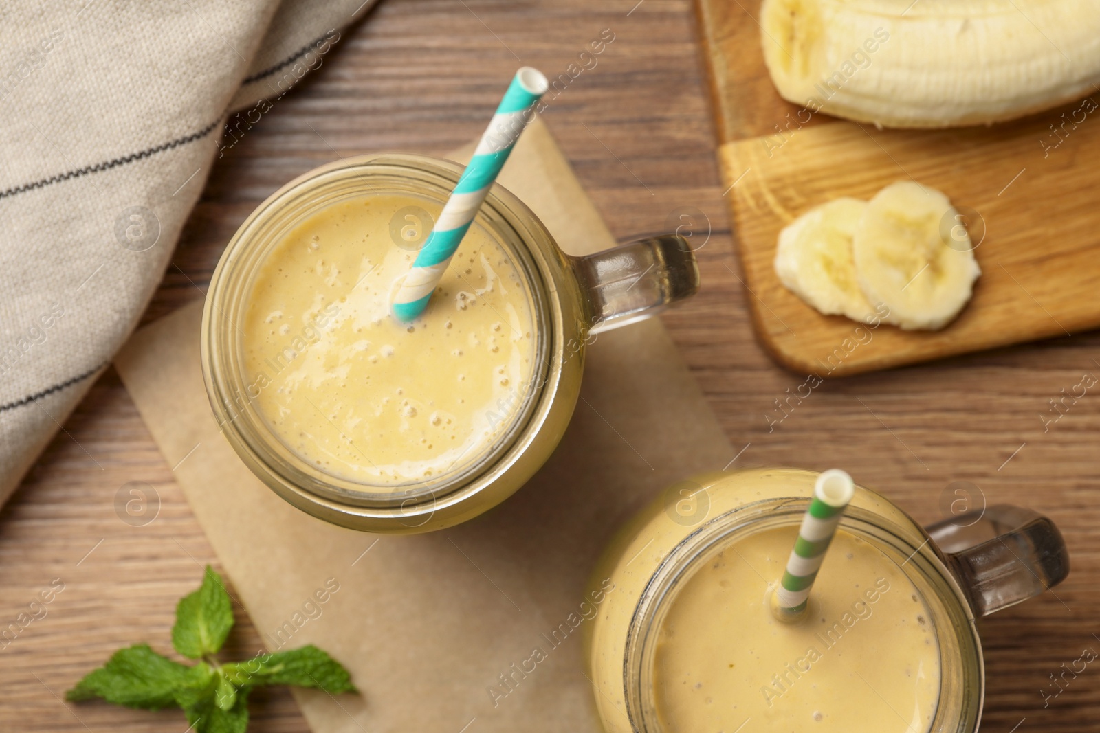 Photo of Tasty banana smoothie and mint on wooden table, flat lay
