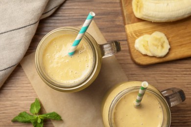 Photo of Tasty banana smoothie and mint on wooden table, flat lay