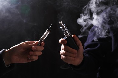 People with electronic cigarettes on black background, closeup