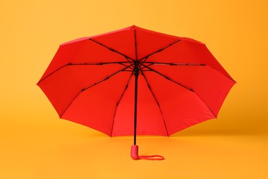 Photo of Stylish open red umbrella on yellow background