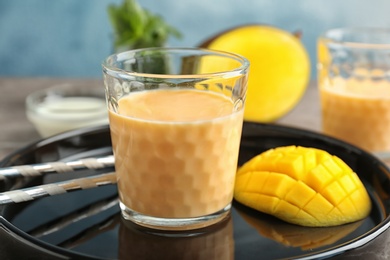 Photo of Glass with healthy detox smoothie and mango on tray