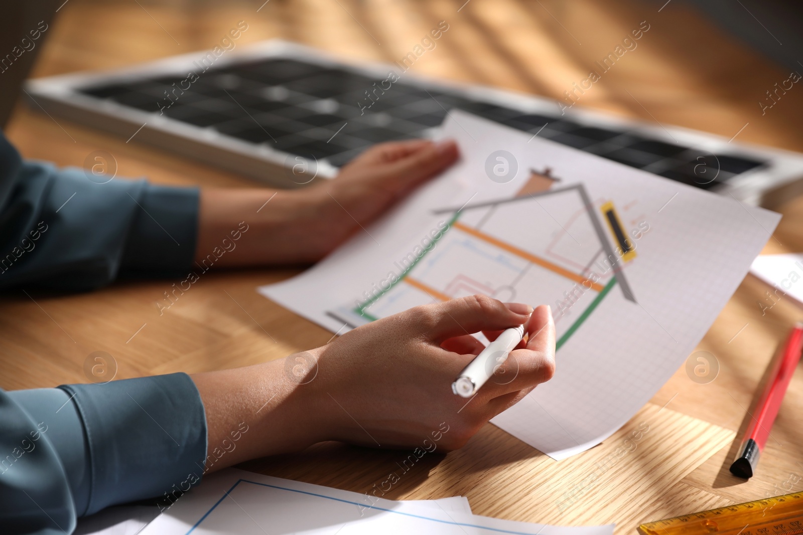 Photo of Woman working on house project with solar panels at table in office, closeup