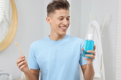 Photo of Young man with mouthwash and toothbrush in bathroom