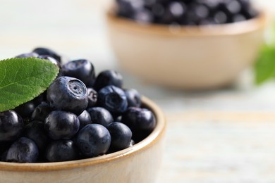 Tasty fresh bilberries in bowl on table, closeup. Space for text