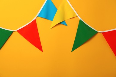 Photo of Bunting with colorful triangular flags on orange background