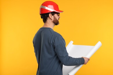 Photo of Architect in hard hat with draft on orange background