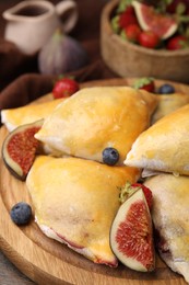 Photo of Delicious samosas with figs and berries on wooden table, closeup