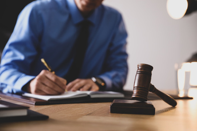 Male lawyer working at table in office, focus on gavel