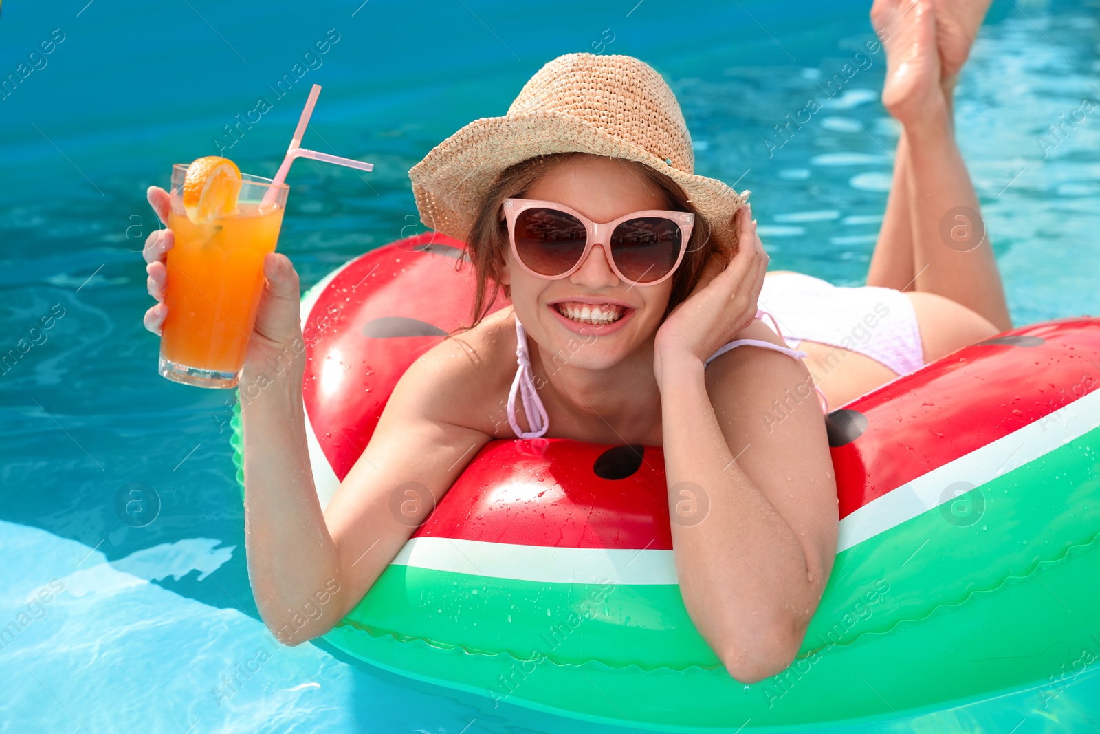 Photo of Young woman with cocktail in pool on sunny day