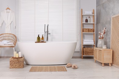 Stylish bathroom interior with bamboo bath mat and white tub