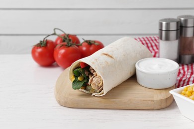 Delicious tortilla wrap with tuna on white wooden table, space for text