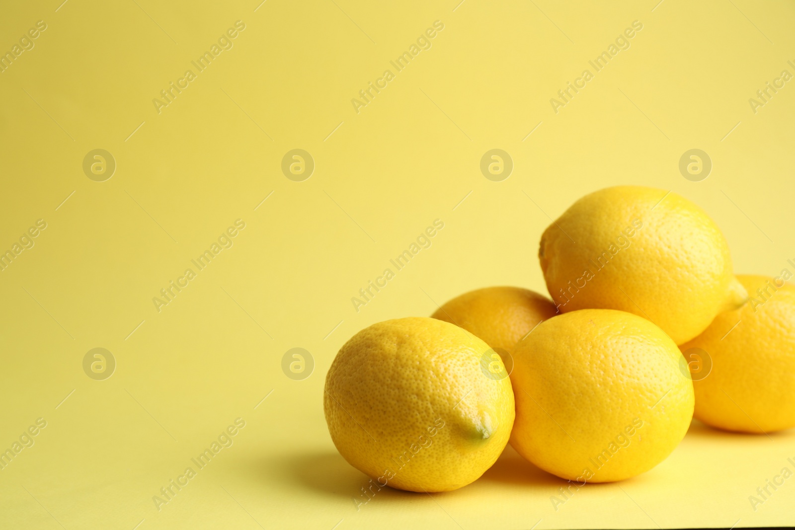 Photo of Fresh ripe lemons on yellow background. Space for text