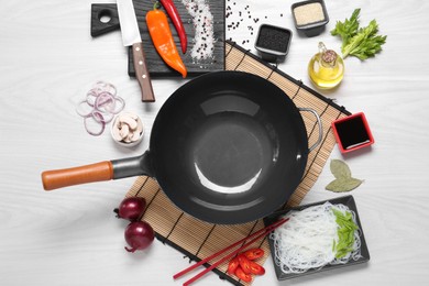 Photo of Wok, chopsticks and different products on white wooden table, flat lay