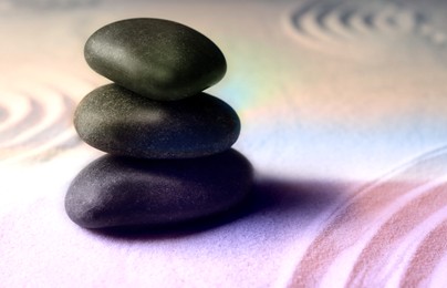 Stacked zen garden stones on sand with pattern, space for text. Meditation and harmony