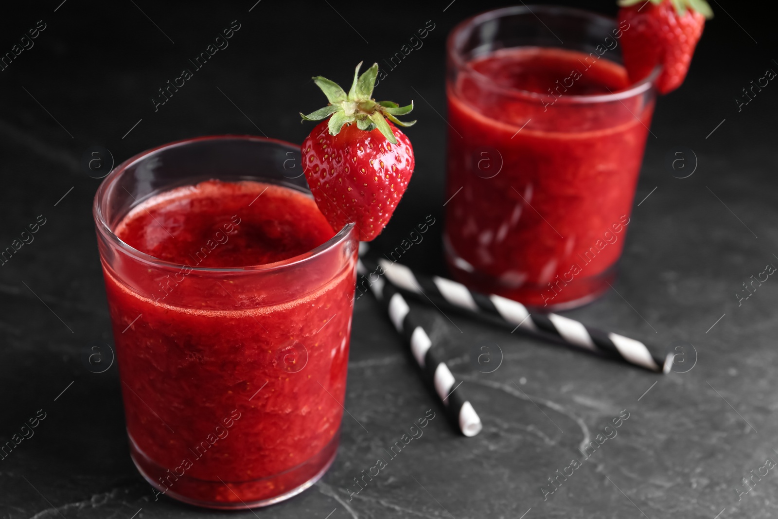 Photo of Tasty strawberry smoothie in glass on black table