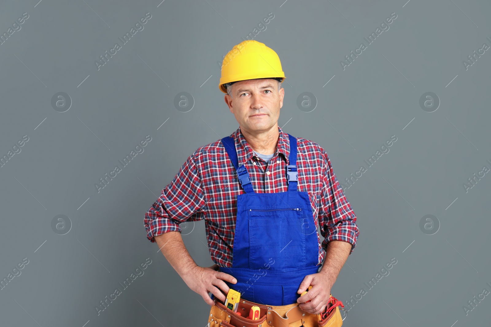 Photo of Electrician with tools wearing uniform on gray background