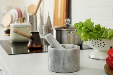 Photo of Marble mortar with pestle on kitchen counter. Cooking utensils