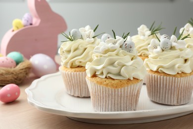 Tasty Easter cupcakes with vanilla cream on wooden table, closeup