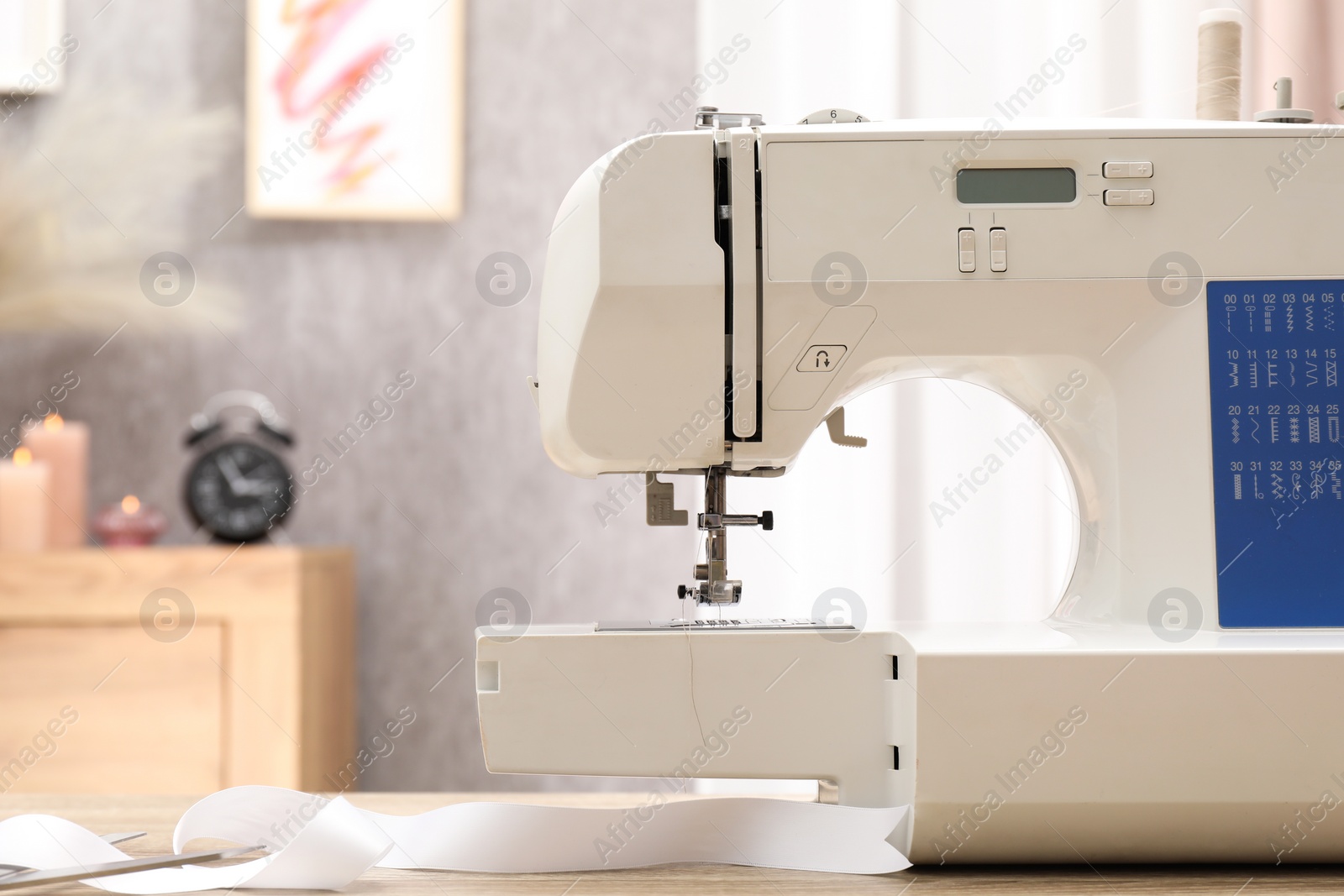 Photo of White sewing machine on wooden table indoors