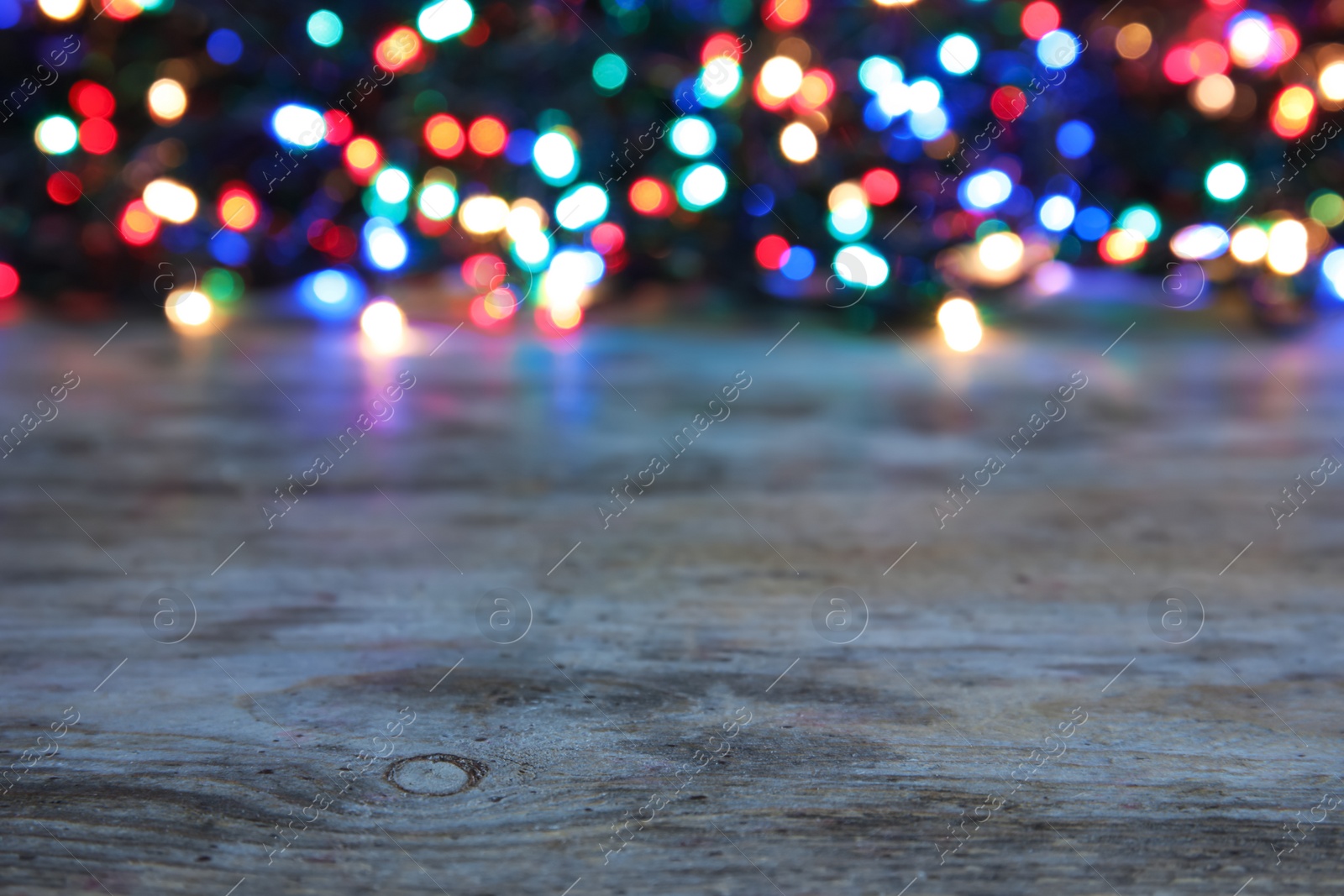 Photo of Wooden table and blurred Christmas lights on background