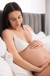 Beautiful pregnant woman in stylish comfortable underwear on bed indoors