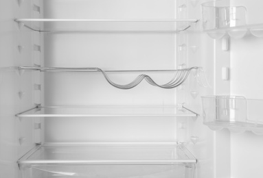 Modern open refrigerator with empty shelves, closeup