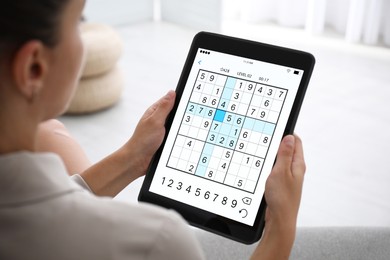 Image of Woman playing sudoku game on tablet indoors, closeup