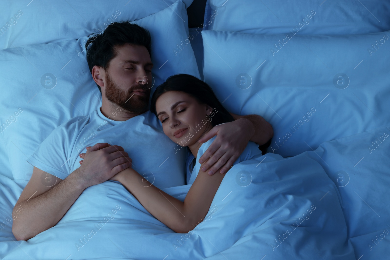 Photo of Lovely couple sleeping together in bed at night, top view