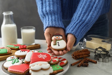Photo of Woman holding delicious homemade Christmas cookie at grey marble table, closeup