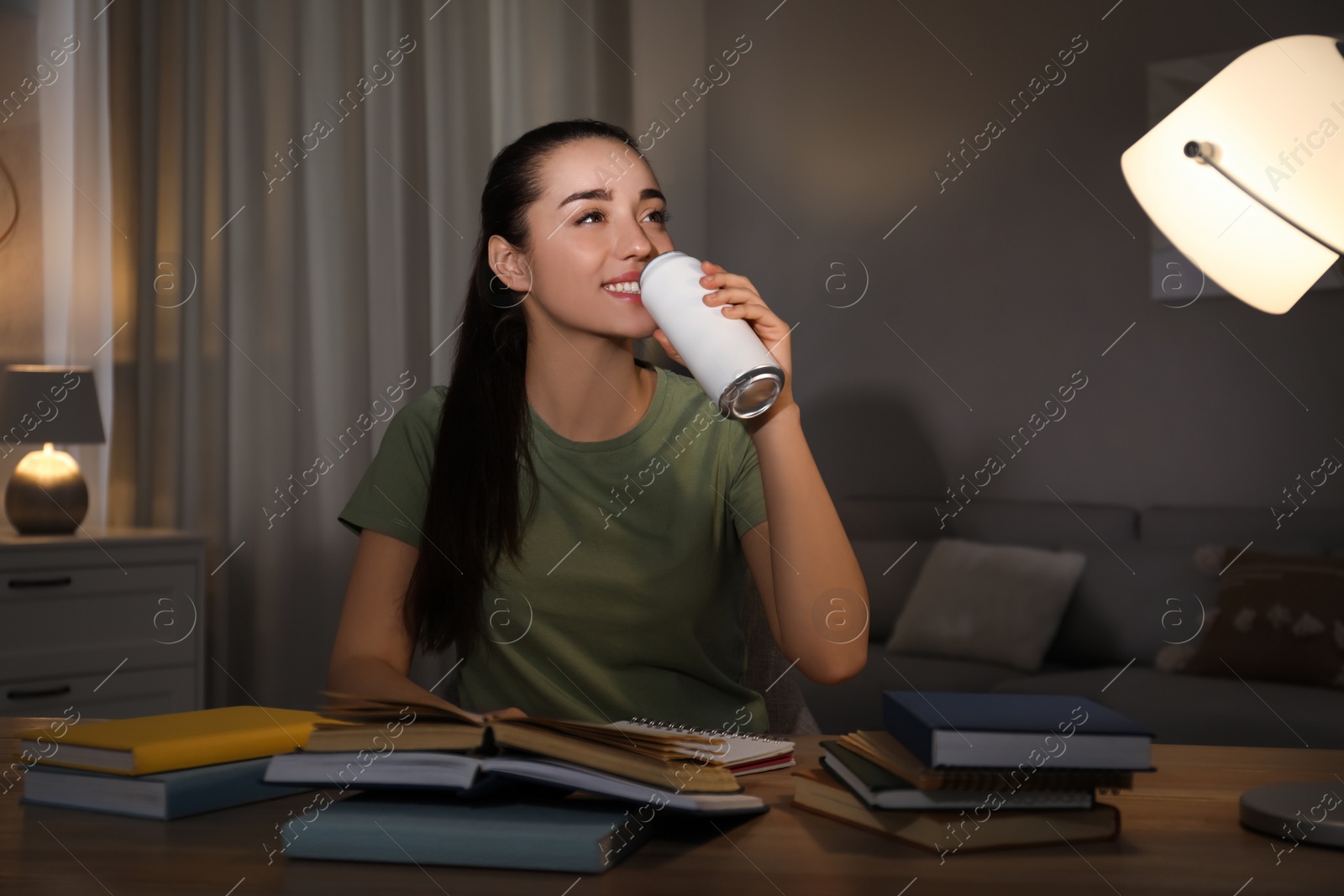 Photo of Young woman with energy drink studying at home