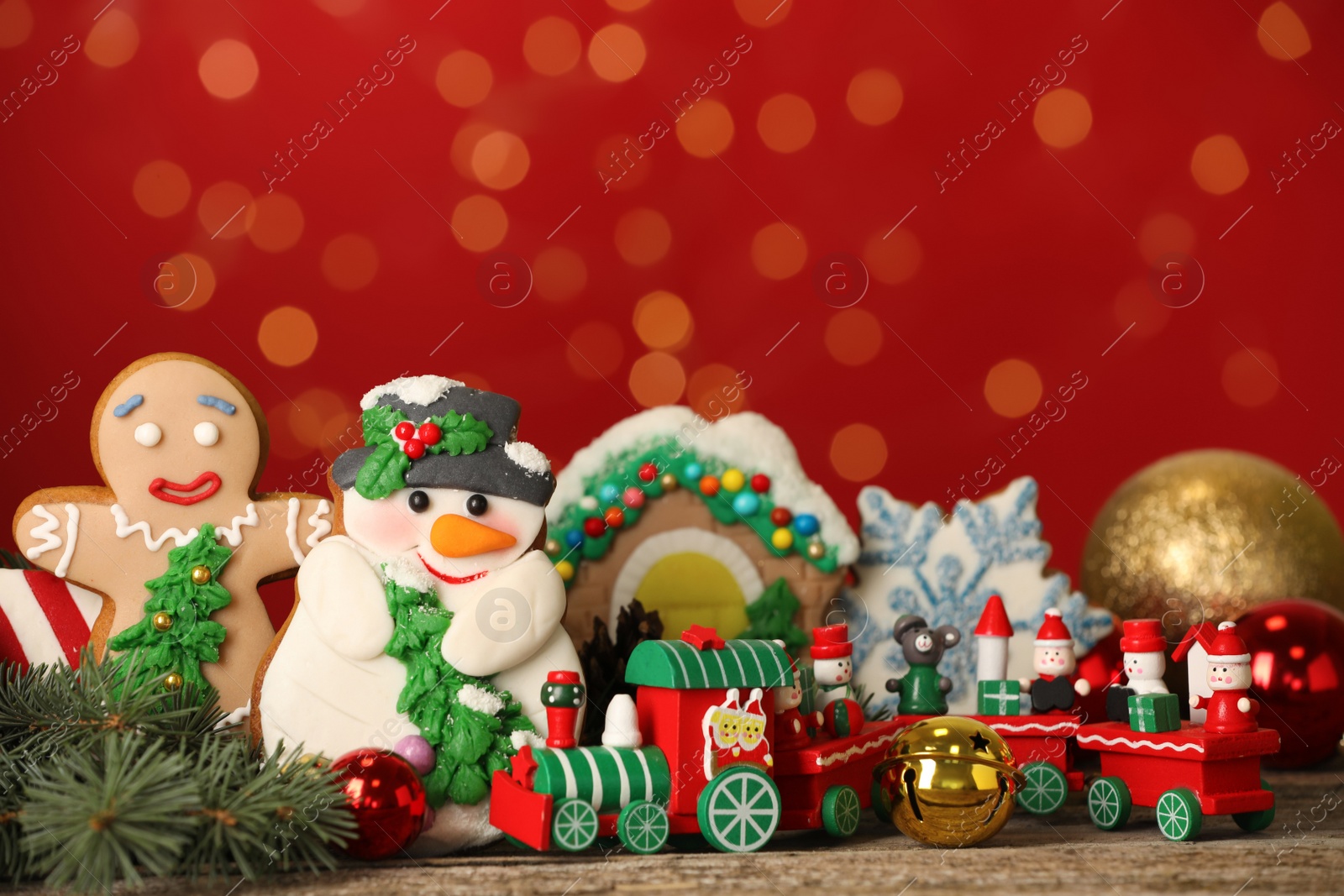 Photo of Sweet Christmas cookies and decor on wooden table against blurred festive lights. Space for text