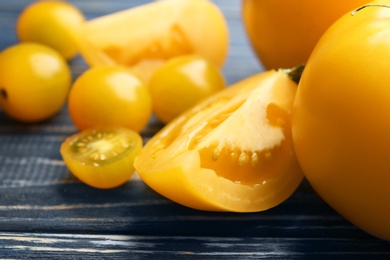 Photo of Ripe yellow tomatoes on blue wooden table, closeup