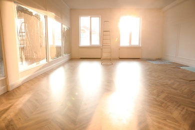 Spacious empty room with new parquet flooring and mirrors