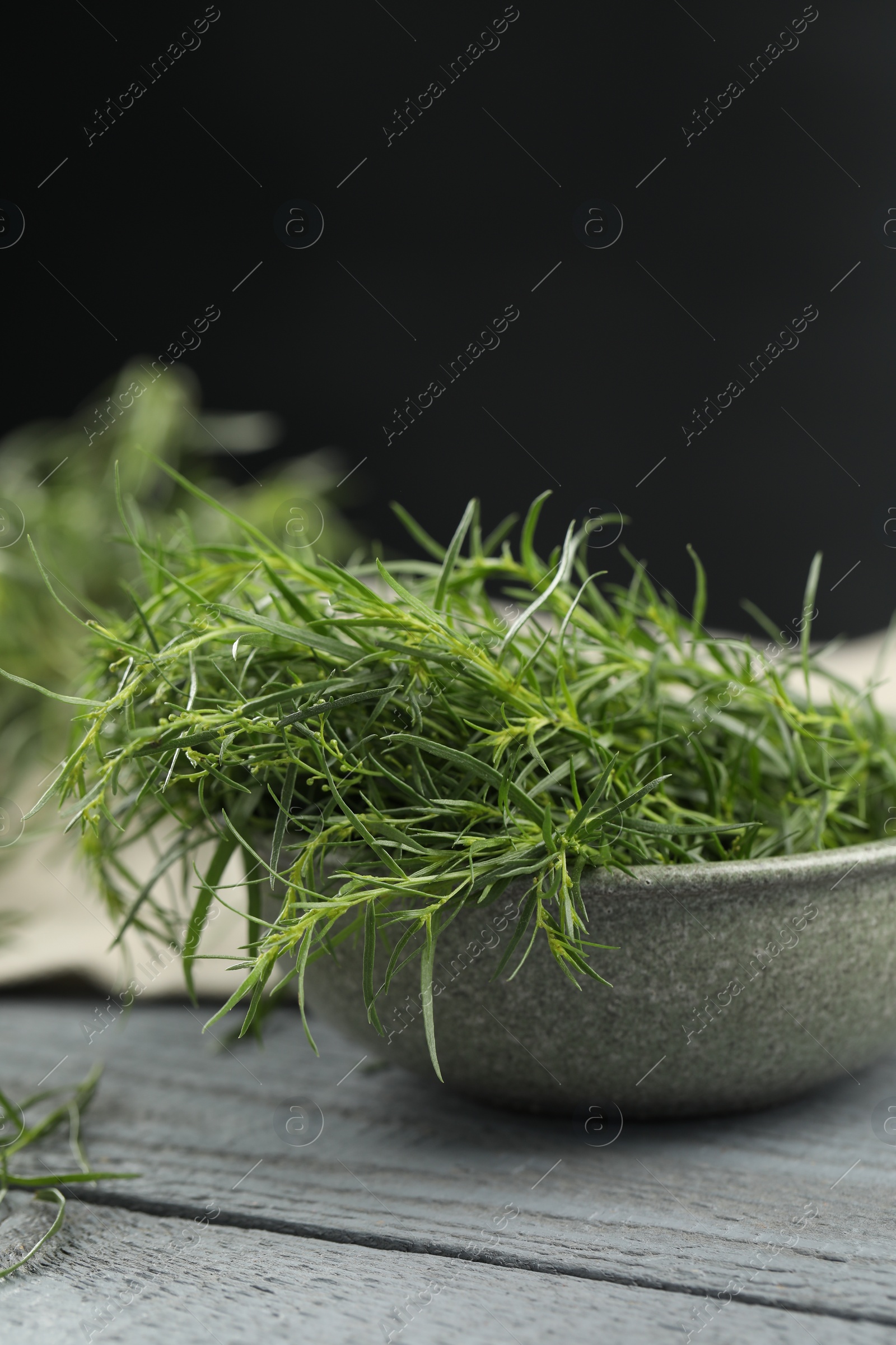 Photo of Fresh tarragon leaves on grey wooden table, closeup