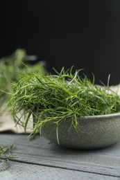 Photo of Fresh tarragon leaves on grey wooden table, closeup