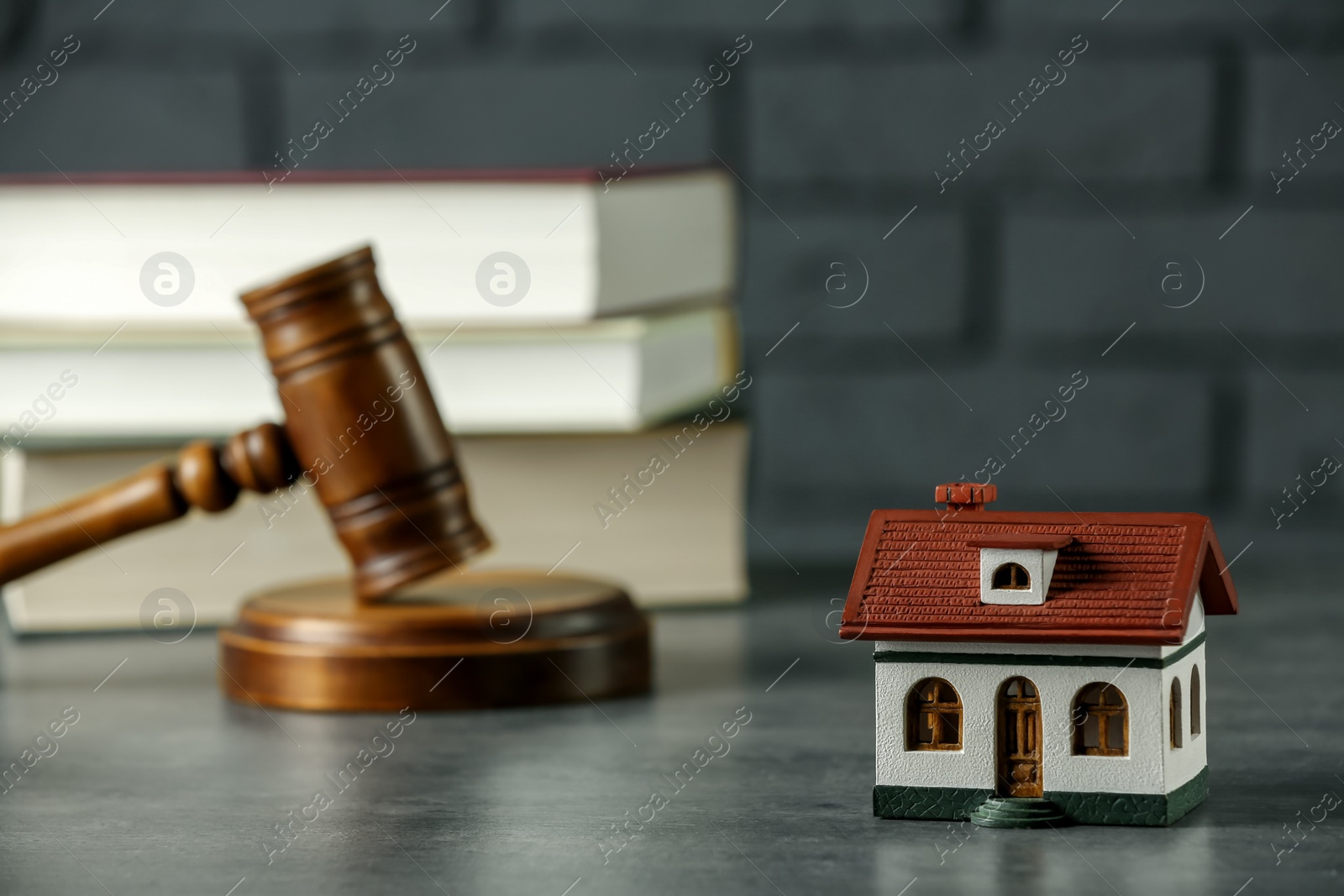 Photo of Construction and land law concepts. Judge gavel, house model with books on grey table